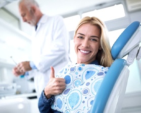 woman smiling and giving thumbs up in dental chair