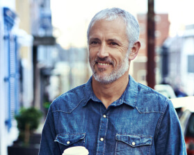 man in jean jacket holding coffee