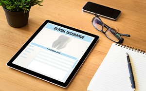 Dental insurance form on tablet on desk with notepad