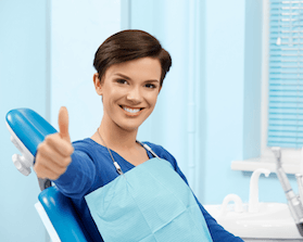 Woman in dental chair giving thumbs up