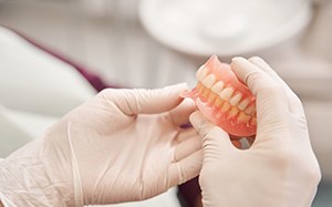 Gloved hands holding removable dentures