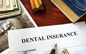 Dental insurance paperwork on wooden desk with X-ray