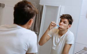 Woman preventing dental emergencies in Bothell by brushing her teeth