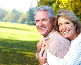 An older couple smiling outside.