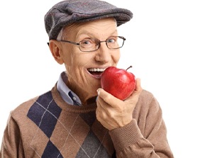 An older man biting into an apple.