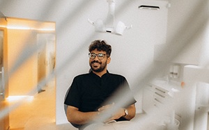 Patient with black glasses smiling in treatment chair