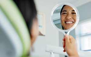 Woman smiling at reflection in dentist office
