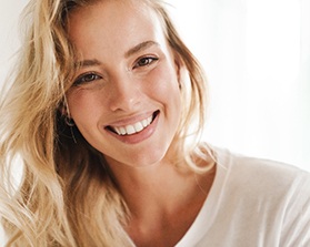 Blonde woman in white shirt smiling at home