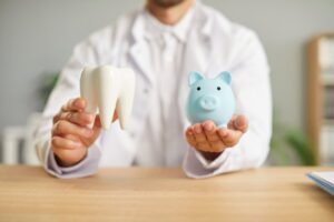 Dentist holding tooth model and piggy bank