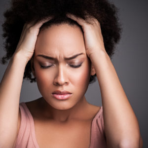 Young African woman suffering from a terrible headache.