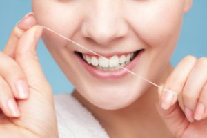 woman smiling while flossing teeth