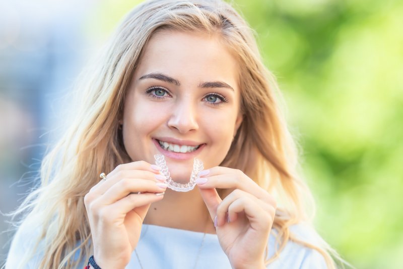 a young woman inserting a clear Invisalign aligner