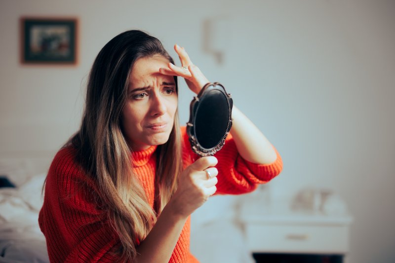 Patient looking in mirror wanting BOTOX for TMJ headaches